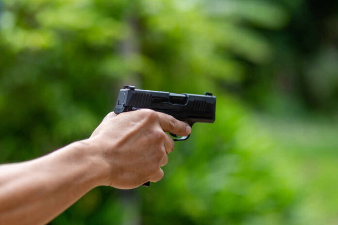 Selective,Focus,Pistol,In,Man's,Hand,Leaning,Forward,In,Shooting