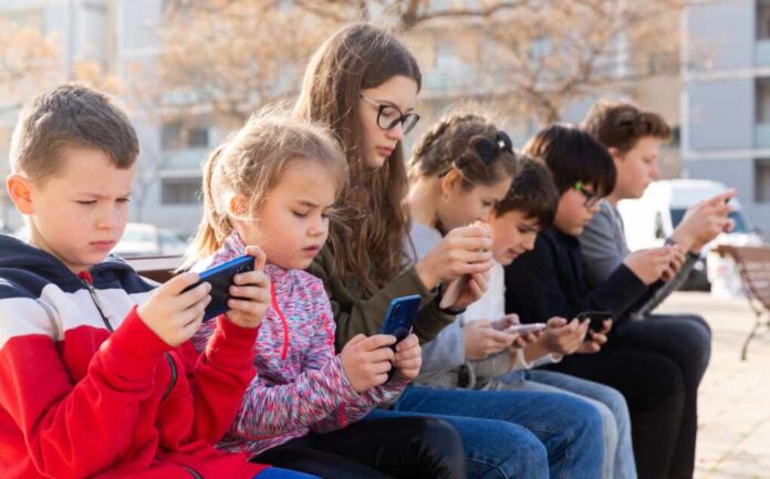 Kids,Using,Phones,Outdoors,,Concept,Of,Children,Addiction,To,Social