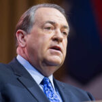 A man in a suit delivering a speech at a podium