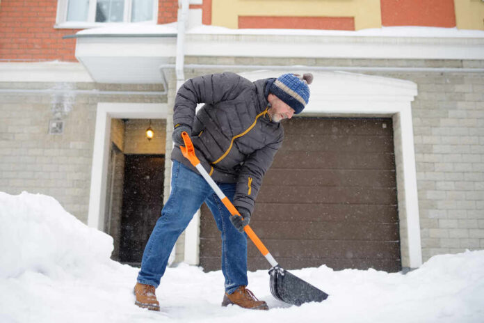 shutterstock_1916740610.jpg Senior man shoveling snow in front of a house