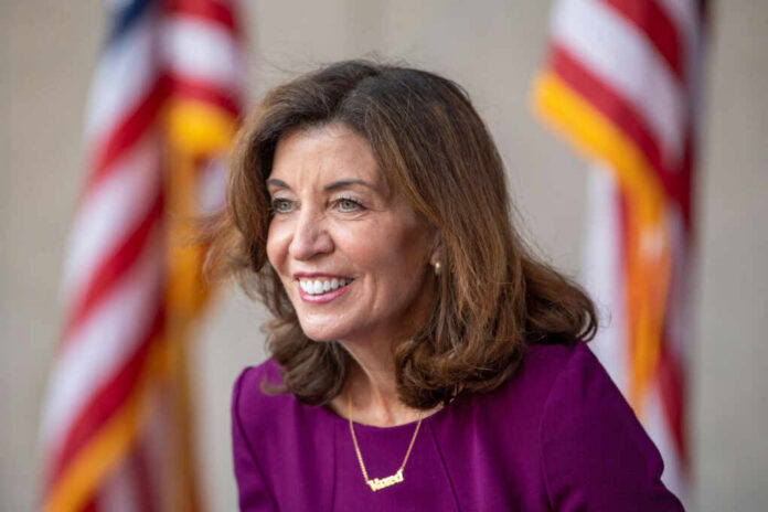 Smiling woman in a purple outfit with American flags in the background