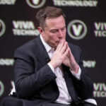 A man in a suit with a thoughtful expression at a technology conference