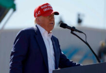 A man in a red cap speaking into a microphone at an outdoor event