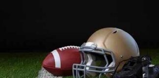 A football helmet, a football, and cleats on a field