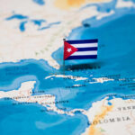 TRUMP Floats “Friendly Takeover” Of Cuba A small Cuban flag placed on a map highlighting Cuba in the Caribbean