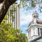 View of a historic government building with a dome and surrounding trees