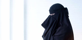 Woman wearing a black abaya, partially turned to the side