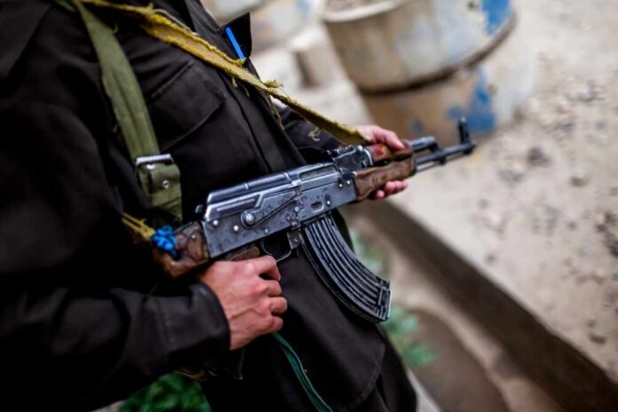 Soldier holding an AK-47 rifle in a conflict area