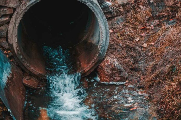 Water flowing from a drainage pipe into a grassy area