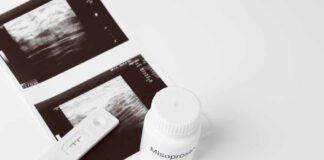 Ultrasound images and a bottle of misoprostol next to a pregnancy test