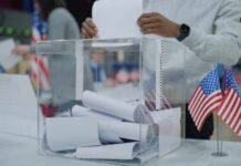 Person casting a vote into a transparent ballot box during an election