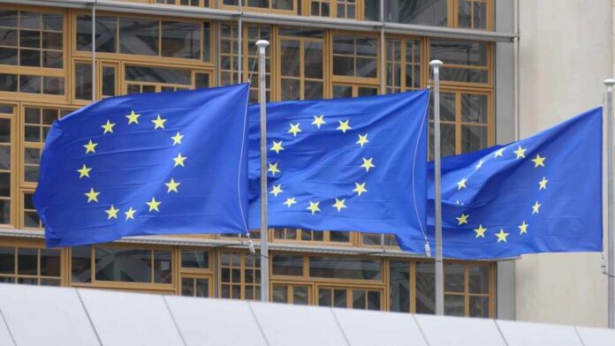 Three European Union flags waving in front of a building