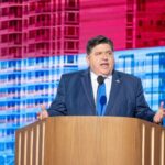 A government official delivering a speech at a podium with a colorful backdrop