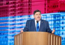 A government official delivering a speech at a podium with a colorful backdrop