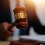 A judge's gavel being raised in a courtroom setting