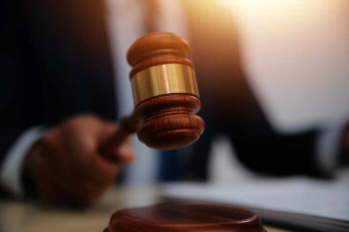 A judge's gavel being raised in a courtroom setting