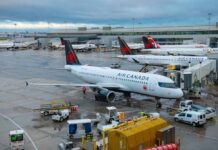 Air Canada planes parked at an airport terminal with ground crew working