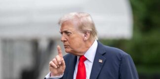 A political figure gesturing with a finger raised during a press conference