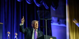 A speaker at a podium gesturing during a political event