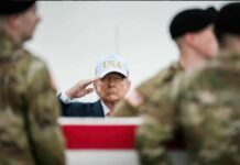 A man in a USA cap saluting in front of soldiers