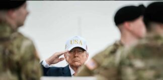 A man in a USA cap saluting in front of soldiers
