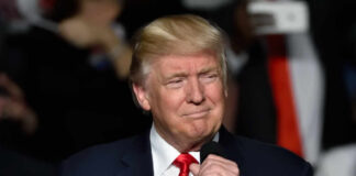 Donald Trump speaking at a rally with a microphone