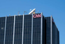 CNN Caught Again? Network’s Credibility Crumbles The top of the CNN building featuring the logo and broadcasting equipment against a clear blue sky