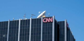 The top of the CNN building featuring the logo and broadcasting equipment against a clear blue sky