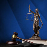 Decades-Long Killing Spree Exposed—Chilling Revelations Bronze statue of Lady Justice holding scales next to a gavel on a book