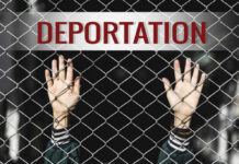 Hands reaching through a metal fence with the word DEPORTATION above