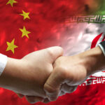 Handshake between two individuals with Chinese and Iranian flags in the background