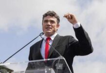 SEAL Team Rescue EXPOSES Former Official’s Betrayal Man in a suit delivering a speech at an outdoor event