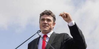 Man in a suit delivering a speech at an outdoor event