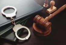 Handcuffs and a gavel on a desk with legal books