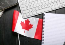 Canadian flag placed on a desk next to a keyboard and a blank notebook