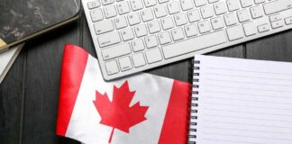 Canadian flag placed on a desk next to a keyboard and a blank notebook