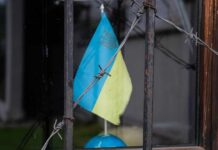 Ukrainian flag partially visible behind barbed wire in a window