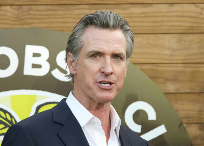 A man in a suit speaking at an outdoor event with a microphone