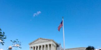 U.S. Supreme Court building with American flag and blue sky