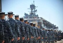 Uniformed naval personnel marching towards a ship
