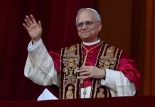 A religious leader in papal attire waving from a balcony