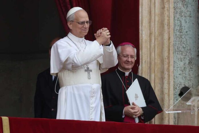 A religious leader in white robes gestures during a public address