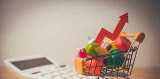 A shopping cart filled with colorful grocery items next to a calculator and an upward trend arrow