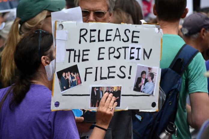 A person holding a protest sign that reads 'Release the Epstein Files' with photos attached