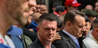 ISIS Death Threat Puts Activist on High Alert A group of individuals at a protest holding a banner