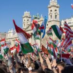 A large crowd waving Hungarian flags at a political rally