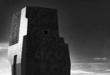 A modern architectural structure in black and white against a cloudy sky