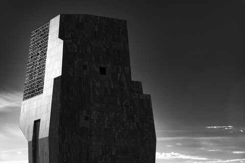 A modern architectural structure in black and white against a cloudy sky
