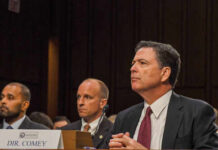 A man in a suit sitting at a table during a congressional hearing