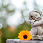 A cherub statue resting beside a bright orange flower